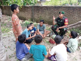 Manfaatkan waktu, Babinsa Komsos Dengan Sejumlah Anak-Anak di Desa Binaan